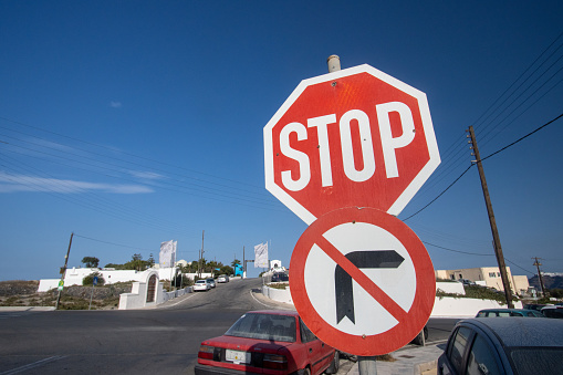 Stop Sign in Pyrgos Kallistis on Santorini in The Cyclades Islands, Greece, with car number plates visible in the background