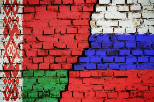 brick wall with a flag of belarus and russia with a big crack in the middle - belarus imagens e fotografias de stock