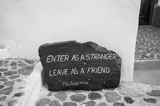 Pyrgos Kallistis on Santorini in South Aegean Islands, Greece with an Ancient Greek saying on a volcanic rock: 'enter as a stranger, leave as a friend'.