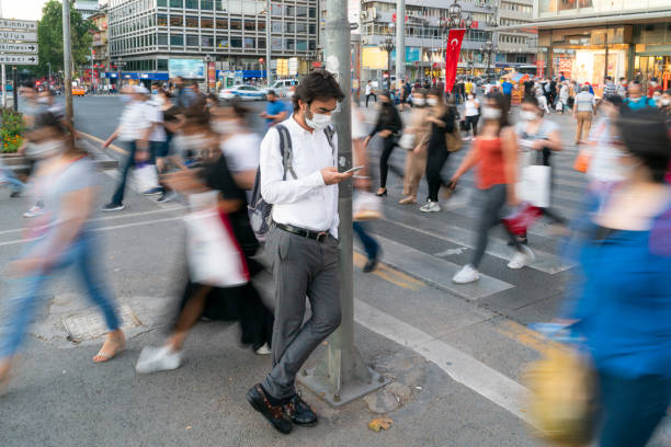 横断歩道で待っている間に電話を使っている男 - crosswalk crowd activity long exposure ストックフォトと画像
