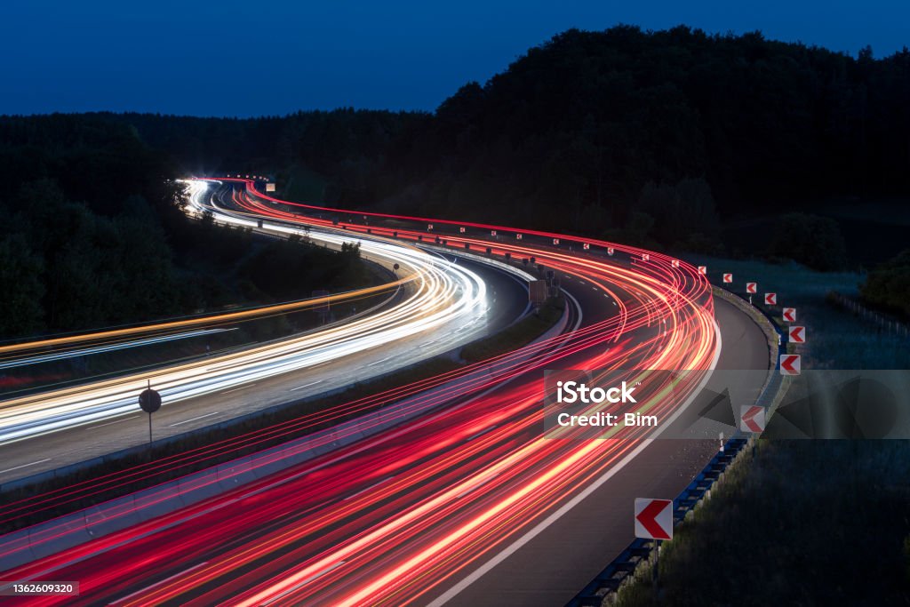Car Light Trails on Highway at Night Long exposure of car lights on motorway meandering through Hills in Bavaria, Germany. Transportation Stock Photo