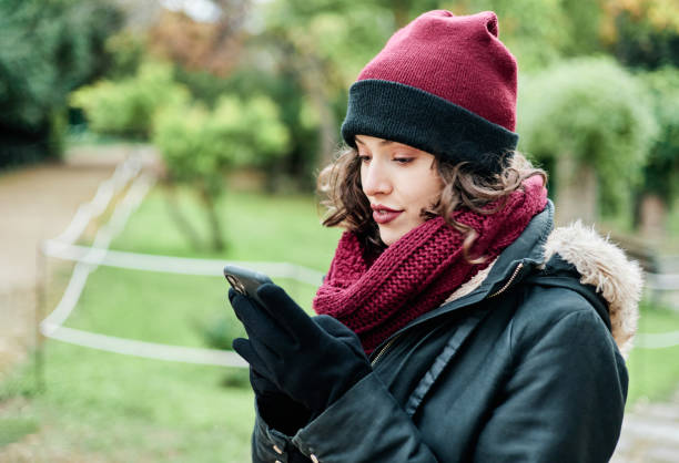 istock Young girl with mobile phone in winter clothes. 1362611892