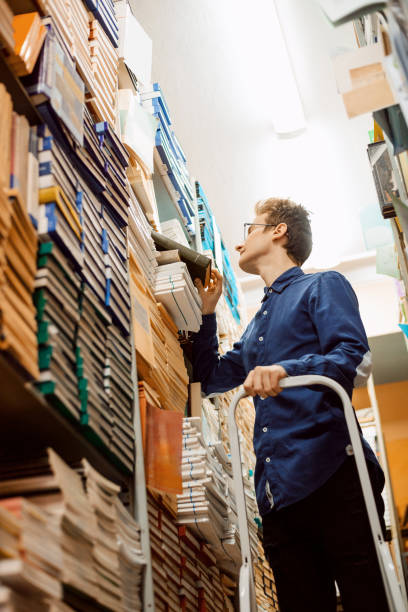istock Young intelligent man looking for science materials in the local archive, prepare to write master work 1362611948