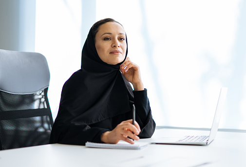 Hermosa mujer árabe con vestido de abaya trabajando en la oficina photo