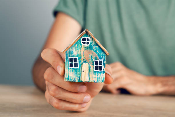 istock a man holding a house by the table 1362615390