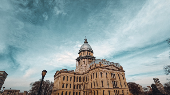 The Capitol dome stands tall against a winter afternoon cloudscape. Illinois State Capitol Building in Springfield, Illinois.