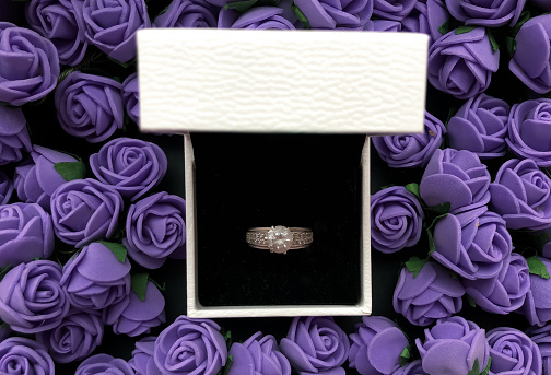 In the jewellery box a ring on background from flowers in color of the year 2022 very peri. Romantic concept.
