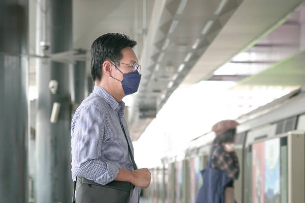 istock Man commuter with face mask on standing on the subway platform waiting to go inside train. Masked transit concept. 1362617960