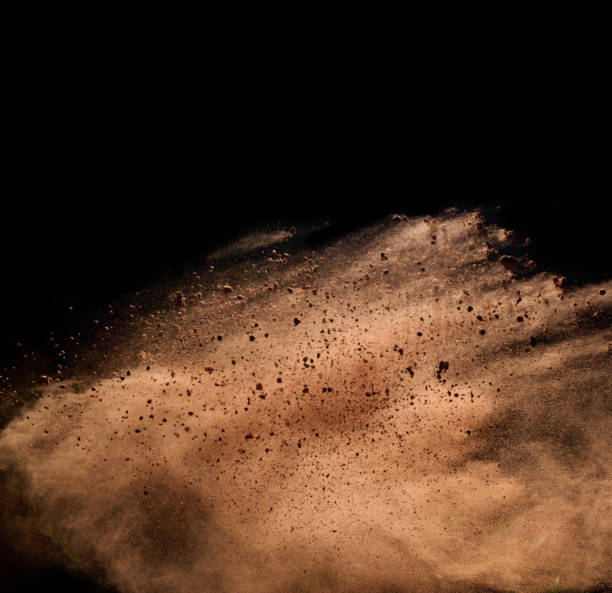 istock flying brown cocoa particles on a black background. Powder flies up 1362618131