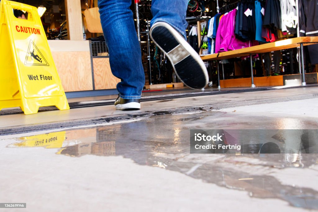 Wet floor in a retail store. Slips, trips and falls are a major cause of injury.  An occupational healthy and safety topic. Store Stock Photo