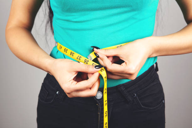 istock young woman measuring belly with tape 1362620986