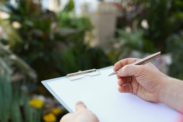 istock Human hand writing on clipboard with white paper, pen and blank document 1362624511