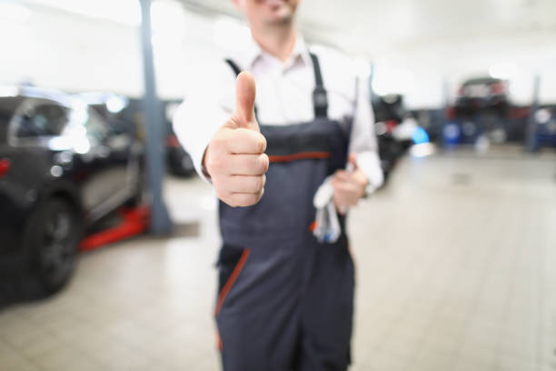 istock Male worker in uniform showing thumbs up posing in garage 1362624533