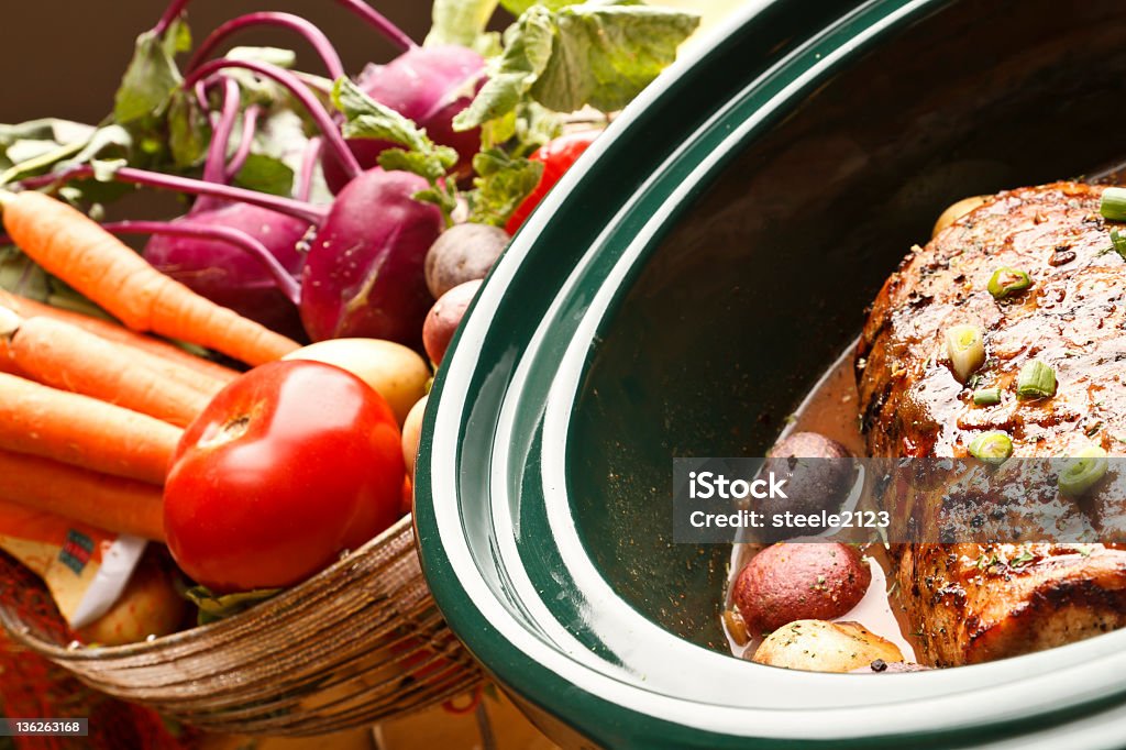 Delicious Looking Dinner Pot roast, in a crock pot, resting in front of fresh vegetables.  Critical focus is on the roast. Crock Pot Stock Photo