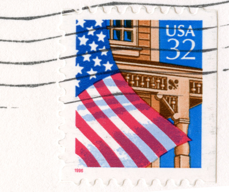Postmarked stamp of the US flag waving from a wooden porch on a building. 32 cents.