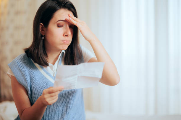 woman receiving an expensive utility bill having a migraine - fine print imagens e fotografias de stock