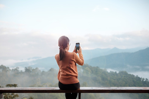 Happy tourist woman taking Photo by mobile smartphone, Blogger looking mountain view. Travel, vacation, journey, trip and relaxing concept