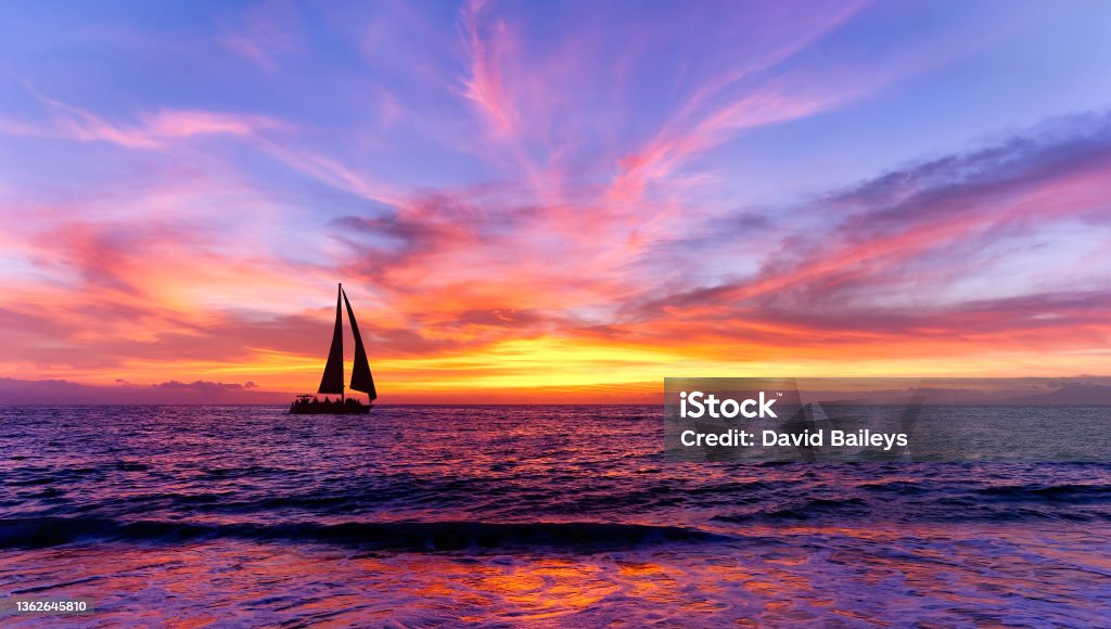 Colorful Sunset Sailboat Ocean Inspirational Landscape A Sailboat Is Sailing Along The Ocean With a Flock Of Birds Flying Overhead Against A Colorful Sunset Sky Sailboat Stock Photo