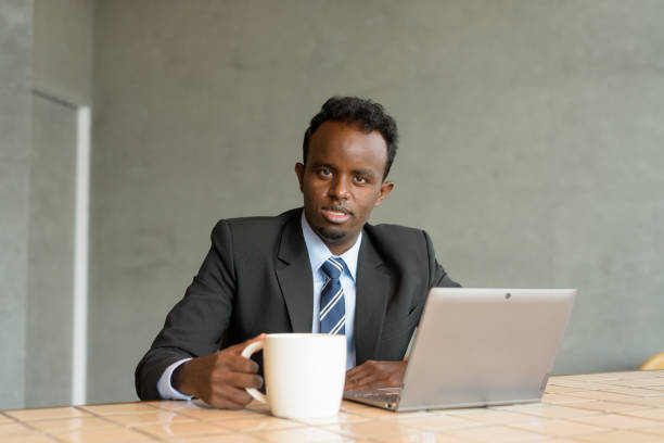 Portrait of young African businessman wearing suit and tie in coffee shop