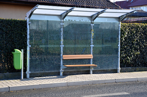 city bus stop. glass shelter with integrated wooden bench. only the roof and the back wall. on the street by the sidewalk in the city. elegant arch, station, platform, subtle