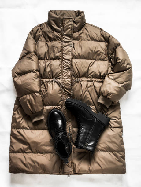 istock Women's down jacket and black leather massive lace-up boots on a light background. Top view 1362656549