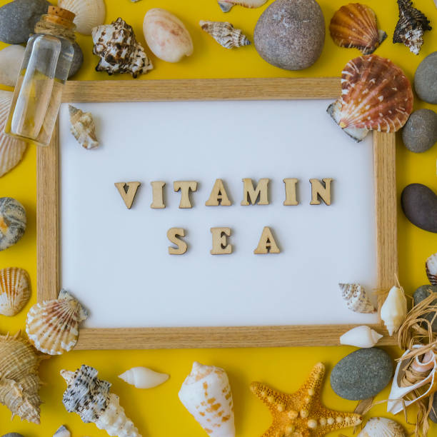 istock Composition sheet white paper text VITAMIN SEA, seashells, pebbles, mockup on yellow background. Blank, top view, still life, flat lay. sea vacation travel concept tourism and resorts 1362665662