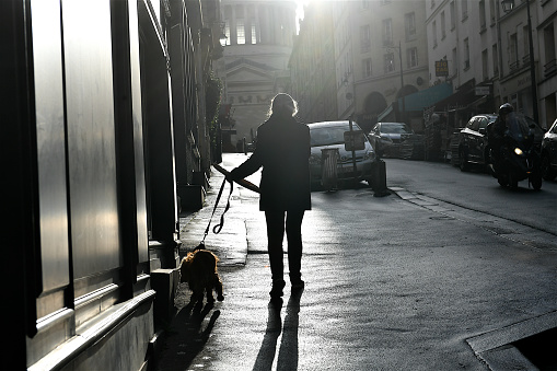 Paris, France-12 27 2021: A woman and her dog in a street of Paris, France.