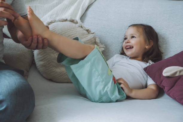 Father plays with little daughter 2-4 on couch. Dad tickles kids feet. Family, having fun stock photo