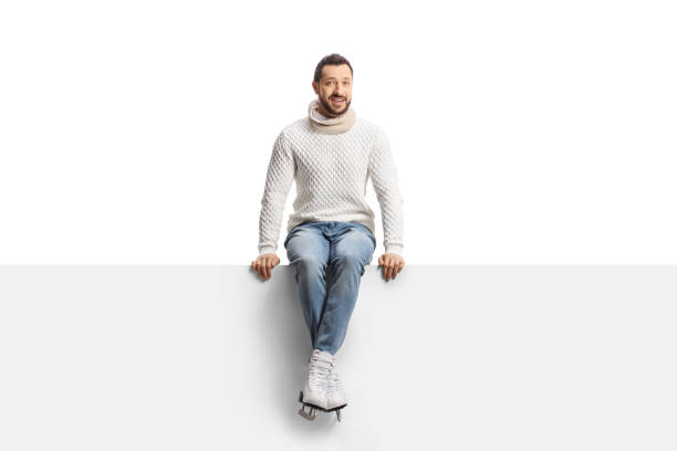 istock Casual young man wearing ice skates and sitting on a blank panel 1362675761