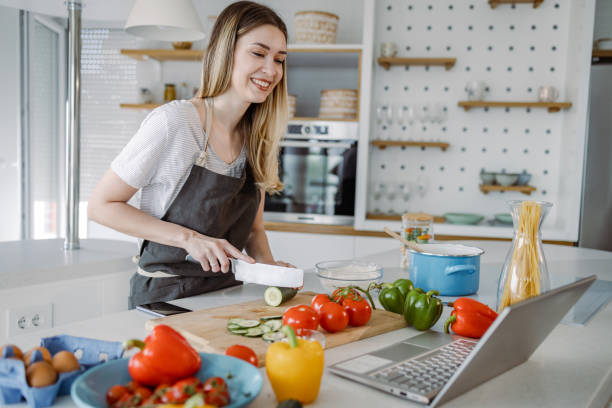 istock Young woman chopping food and looking at online tutorial 1362679740