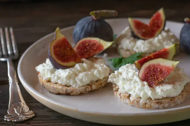 Fresh and homemade breakfast plate with brown rice cracker, topped with cottage cheese and fresh figs. Healthy meal for dieting, fitness or body building. High protein