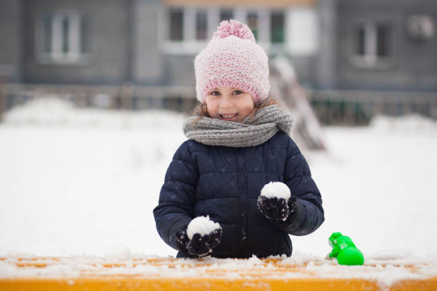 close-up retrato de uma menina alegre segurando bolas de neve - playground snow winter little girls - fotografias e filmes do acervo