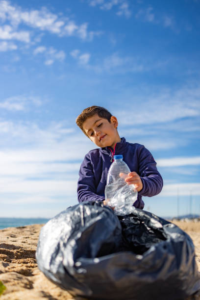 criança pegando plástico na praia. conceito de reciclagem - water child bottle little boys - fotografias e filmes do acervo