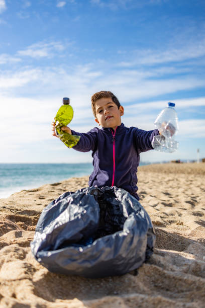 criança pegando plástico na praia. conceito de reciclagem - water child bottle little boys - fotografias e filmes do acervo