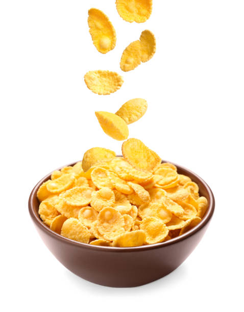 istock Tasty crispy corn flakes falling into bowl on white background. Breakfast cereal 1362686186