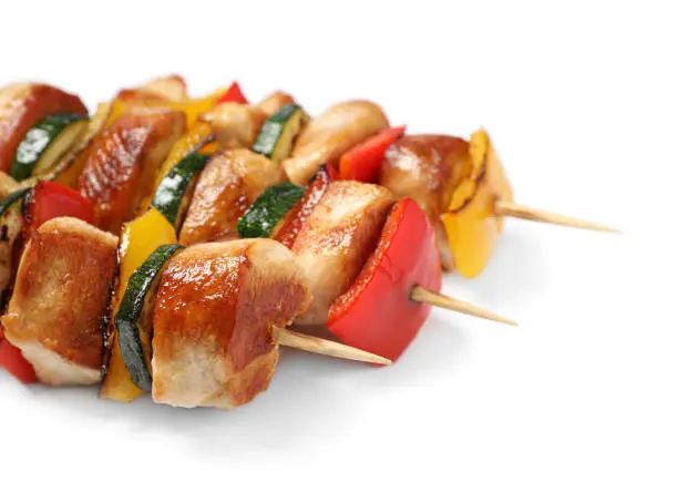 Delicious chicken shish kebabs with vegetables on white background, closeup