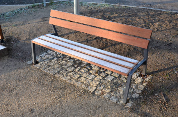 istock Under the bench are rectangles made of tiles. otherwise, the soft surface of the compacted gravel park path could erode the shoes by abrasion. sitting by a small chapel with frozen wooden benches 1362687876