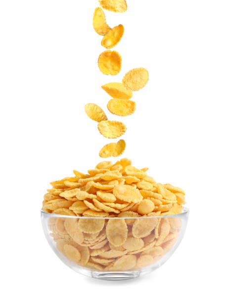 istock Tasty crispy corn flakes falling into bowl on white background. Breakfast cereal 1362689080