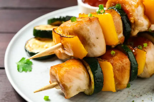 Delicious chicken shish kebabs with vegetables on wooden table, closeup