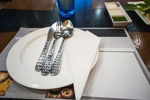 Cutlery set on a white plate on a dinner table in restaurant Bangkok Thailand