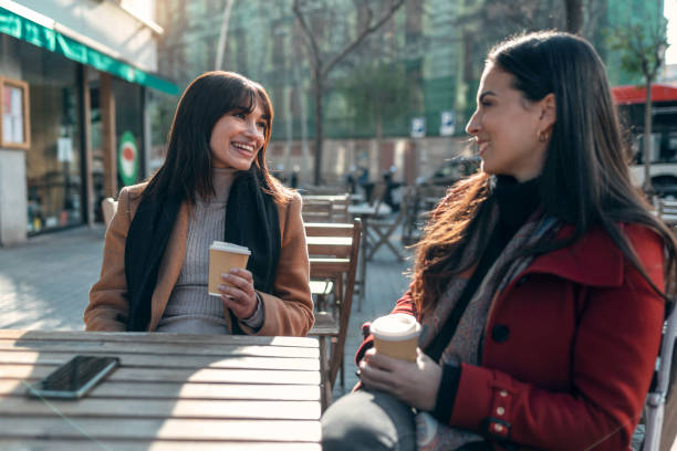istock Two attractive friends enjoying coffee together while talking and laughing sitting on the terrace of a bar. 1362695029