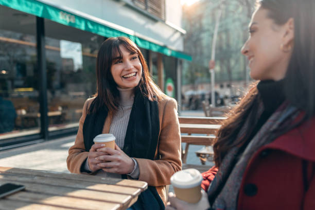 istock Two attractive friends enjoying coffee together while talking and laughing sitting on the terrace of a bar. 1362695577