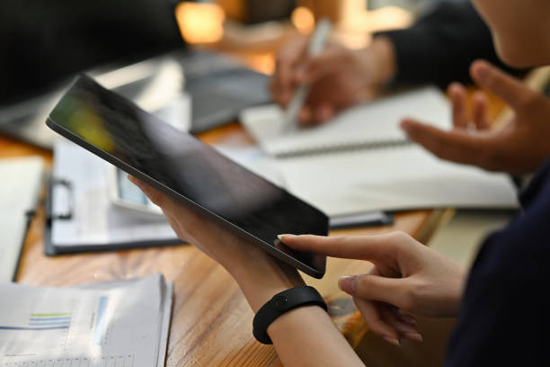 istock Cropped image of young office workers working together with a digital tablet and computer laptop at the cluttered working desk. 1362695861