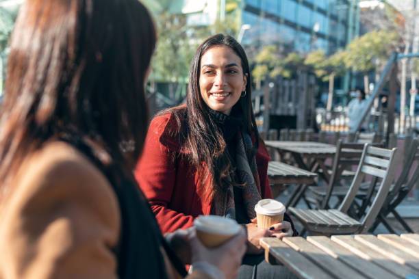 istock Two attractive friends enjoying coffee together while talking and laughing sitting on the terrace of a bar. 1362695924