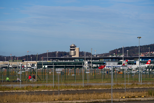 Zürich Airport with air traffic control tower and stationary airplanes on a sunny winter day. Photo taken December 31st, 2021, Zurich, Switzerland.