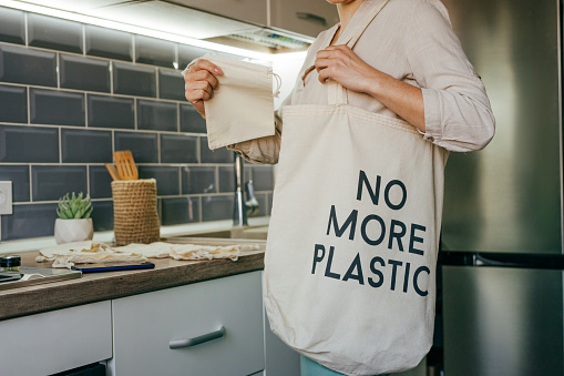Mujer joven que lleva bolsas de algodón reutilizables para ir de compras photo