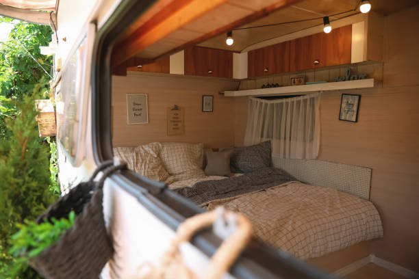 стильный интерьер с удобной кроватью и подушками в современном трейлере, вид снаружи. отдых в кемпинге - pillow bedroom bed rural scene стоковые фото и изображения
