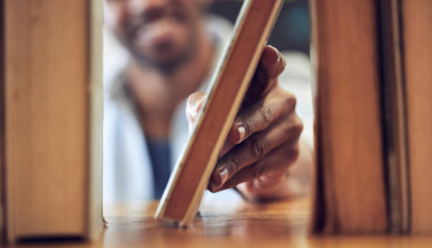 Shot of a man choosing a book to read from a library at college