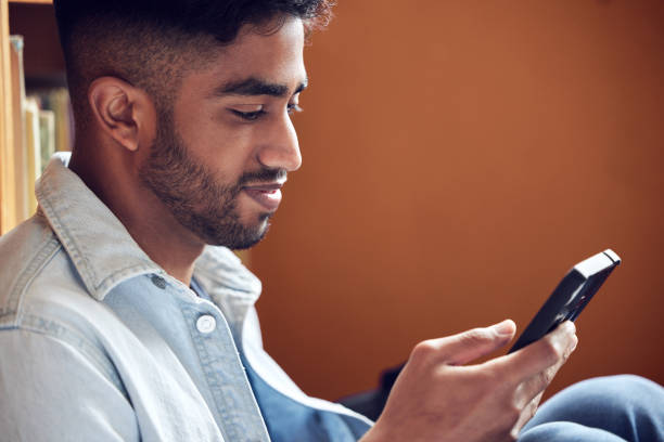 istock Shot of a young man using a smartphone in a library at university 1362700505