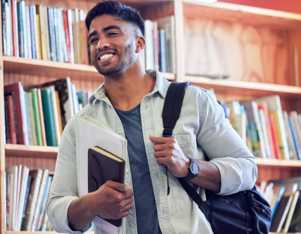 scatto di un giovane che studia in una biblioteca all'università - library student latin american and hispanic ethnicity university foto e immagini stock